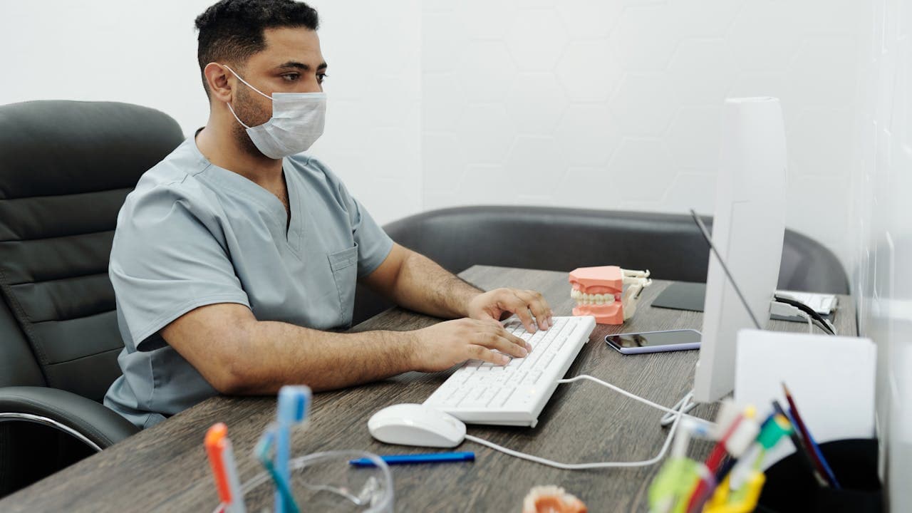 Dentista revisando indicadores de gestión en ordenador de despacho de clínica