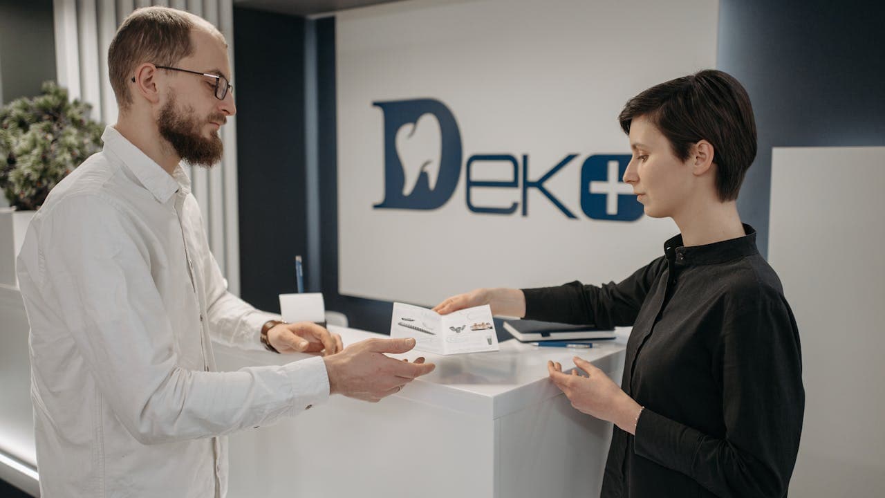 Recepción de clínica dental con paciente y recepcionista durante el registro