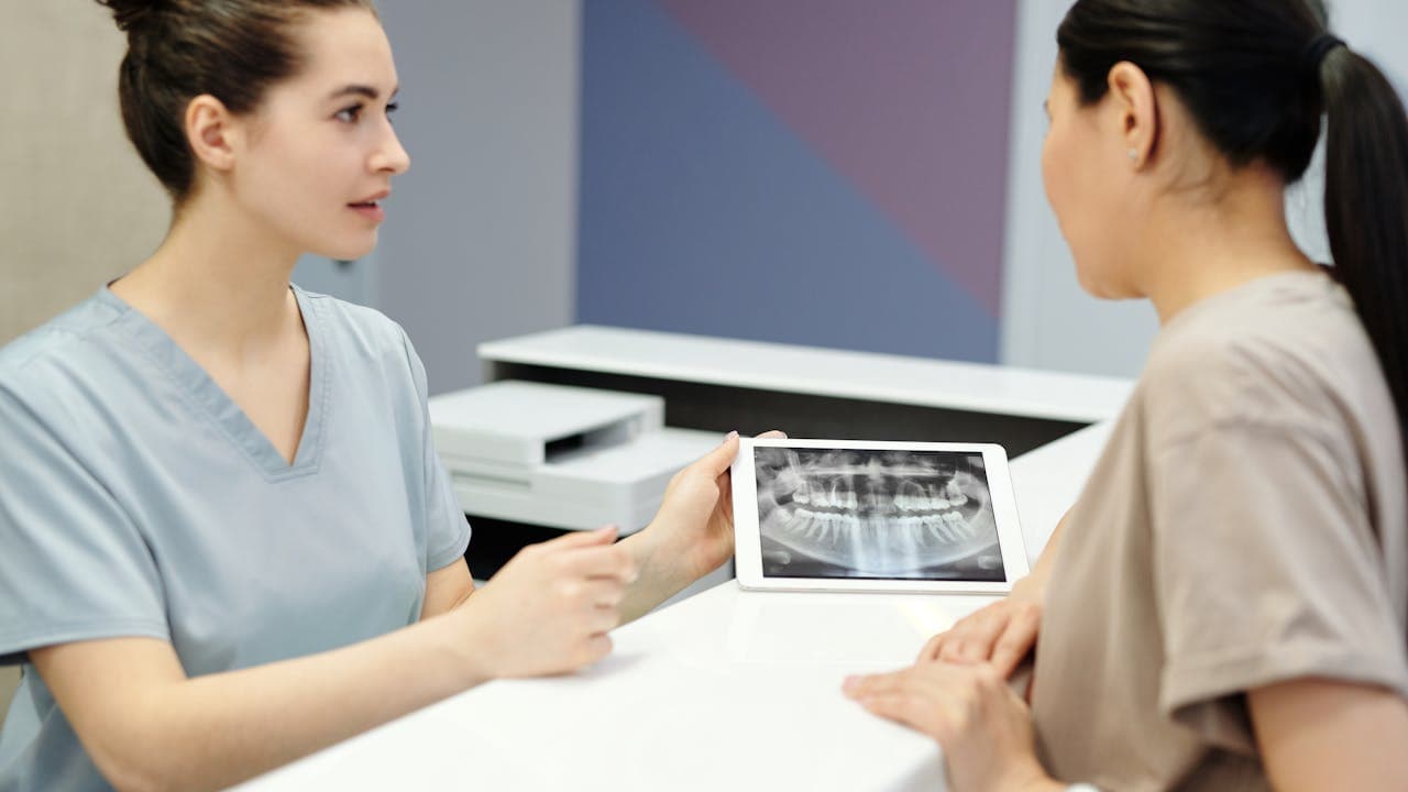 Dentista mostrando una radiografía a un paciente en consulta